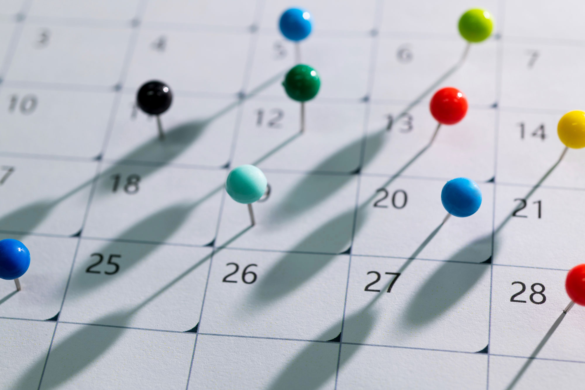 Close-up of coloured pins marking multiple dates on a calendar